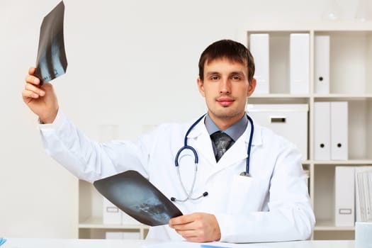 Young male doctor in white uniform at workplace