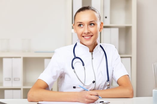 Young female doctor in white uniform at workplace