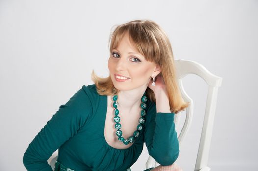 beautiful woman in a green dress sitting on a chair