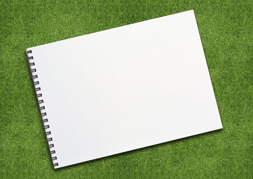 open binder notebook on grassland with empty page.