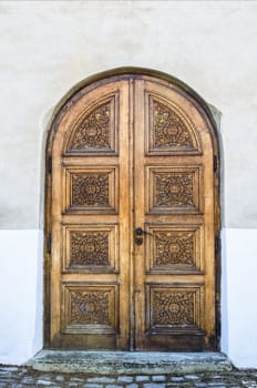 old decorated wooden church door on white wall