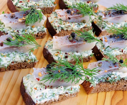 Snack rye bread with butter cream with herbs and spices herring closeup