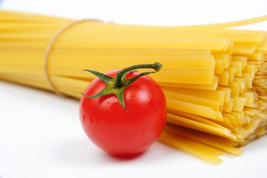 Raw yellow pasta and a red tomato