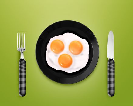 top view of two fried eggs on black Plate between silver knife and fork on gray background.