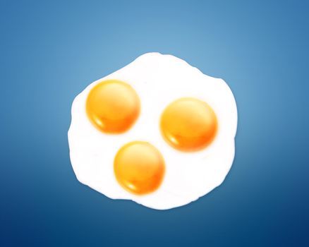 top view of three fried eggs on orange background.