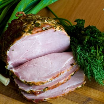 Appetizing slices of ham with potherbs on the kitchen table