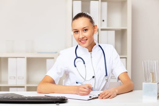 Young female doctor in white uniform at workplace