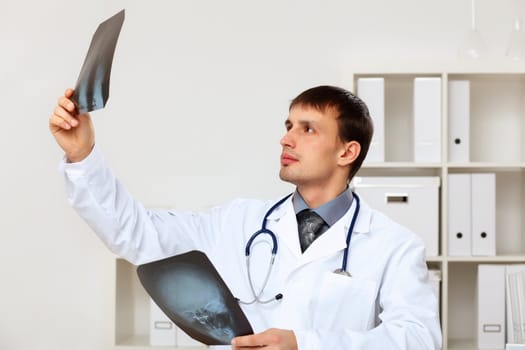 Young male doctor in white uniform at workplace