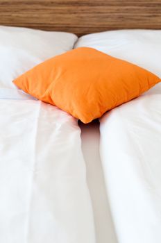 Orange pillow on a bed in a hotel room