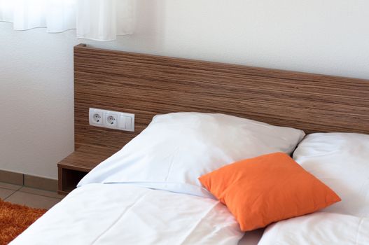 Orange pillow on a bed in a hotel room