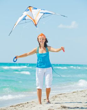 Young cute woman playing with a colorful kite on the tropical beach. Vertikal veiw