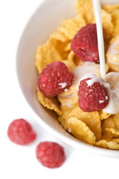 milk pouring into bowl with muesli and raspberry isolated