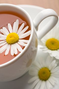 white cup of herbal tea and camomile flowers