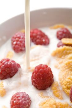 milk pouring onto muesli with raspberry isolated