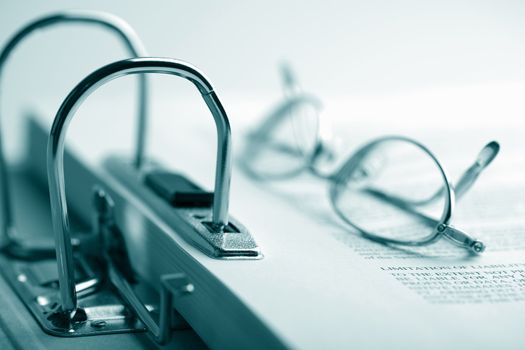 open binder and glasses over document toned blue