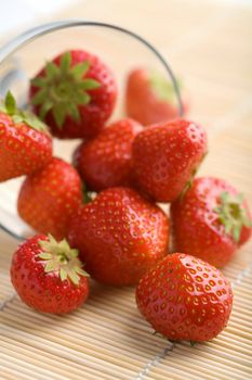 ripe strawberries falling from glass bowl
