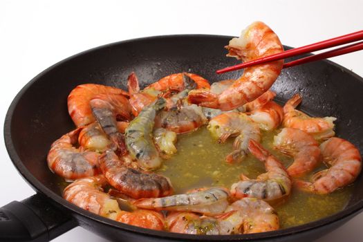 Baking shrimp in a wok with chopsticks