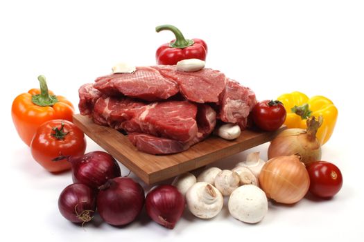 Beef on a wooden plate with ingredients to make goulash