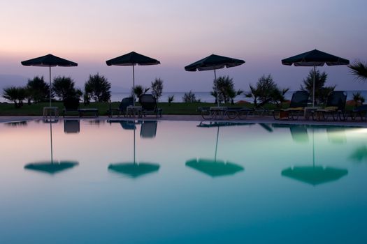 mbrellas silhouettes at the pool by sunset