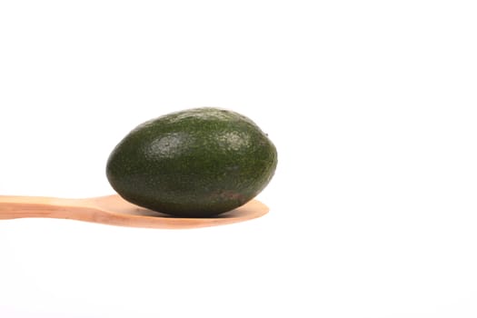Avocado presented on a wooden spoon against a white background