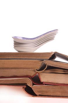 Chinese spoons on a pile of old prescription-books isolated against a white background with copy space