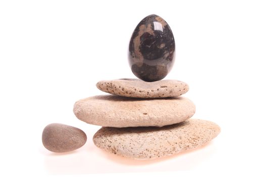 Easter egg on a pile of stones isolated against a white background with copy space