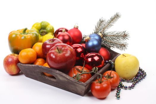 A fruit-dish partially filled with Christmas balls and fruit over white. 