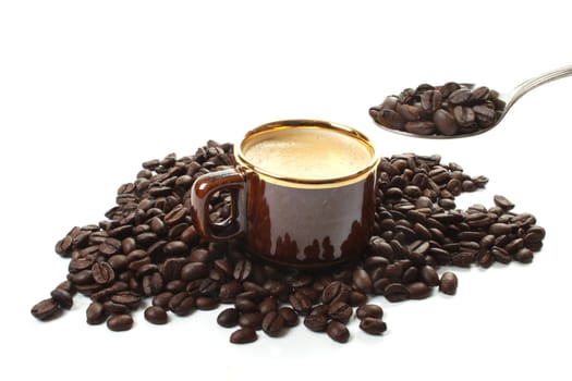 Roasted coffee beans  and a coffee cup to be filled with a spoon