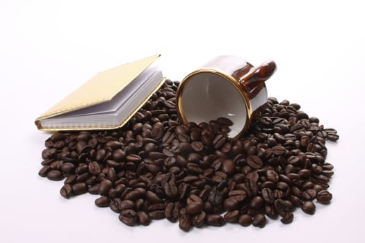 Roasted coffee beans  and a coffee cup and a notebook