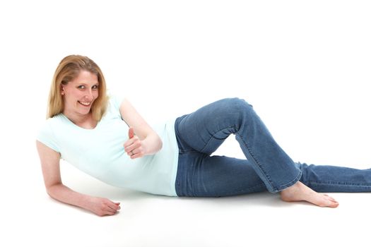 Pretty smiling blonde girl reclining on the floor showing an object in her hand