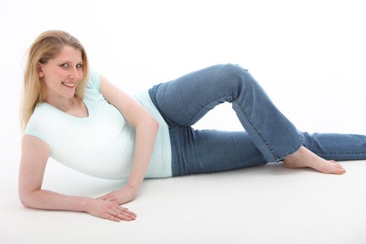 Shaply blonde with a pretty smile laying on the floor relaxing with her legs crossed