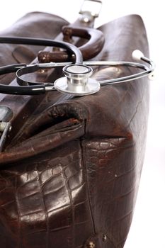 Closeup of a brown leather doctors bag and stethoscope with shallow dof on a white background