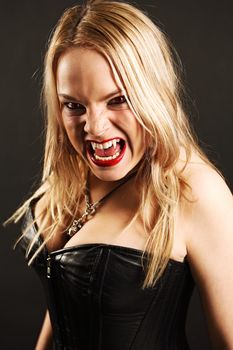 Photo of a female vampire with mouth open and fangs showing.  Harsh lighting and shadows for scarier feel.