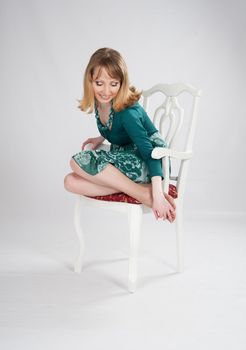 beautiful woman in a green dress sitting on a chair