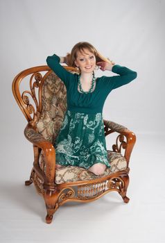 beautiful woman in a green dress sitting on a chair