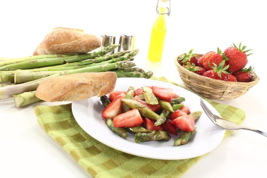 Asparagus salad with fresh strawberries, oil, and bread on a bright background