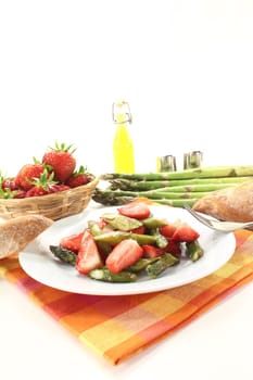 Asparagus salad with strawberries and bread on a light background