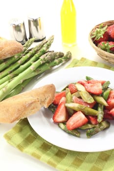 fresh Asparagus salad with strawberries and bread on a bright background