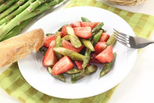 fresh Asparagus salad with fresh strawberries, oil, and bread on a light background