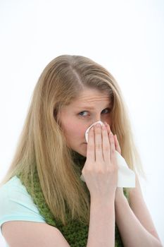 Young woman with a bad cold and sniffly nose wearing a scarf around her neck, trying to stay warm.