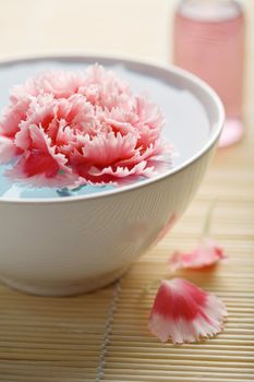 flower in bowl and cosmetic bottle