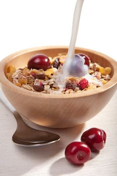 milk pouring onto cereal with fresh berries isolated
