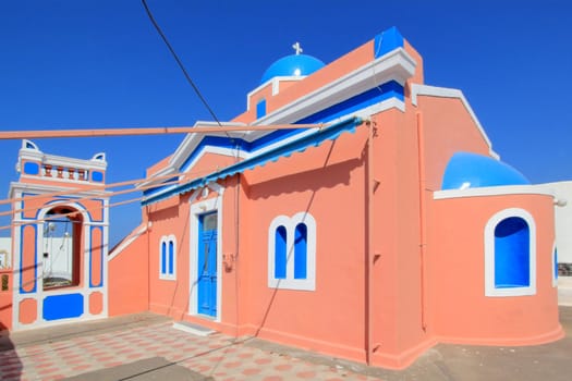 Colorful orthodox church with typical architecture and blue dome in Oia, Santorini island, Greece