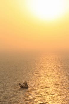 Small old sailing boat on the ocean by beautiful sunset
