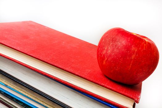 Well used books with an apple sitting on them