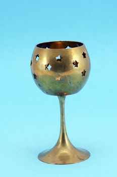 Bronze decorative glass candlestick with star shape holes on blue background.