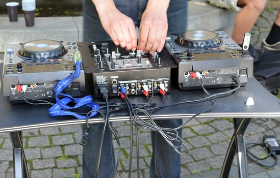 Dj hands play mix track turntable panel in outdoor street music day.