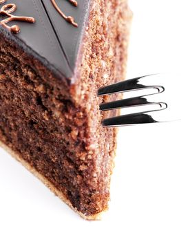 closeup from top of a fork in a chocolate cake on white background