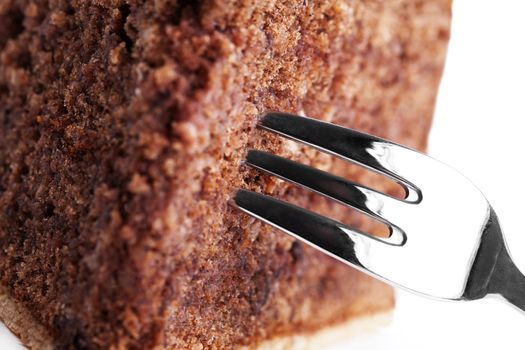 macro closeup of a fork in a chocolate cake on white background