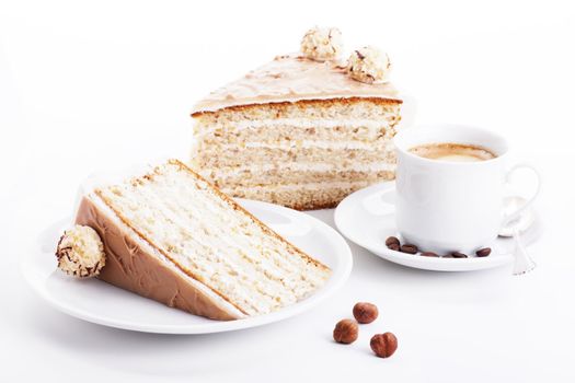 hazelnut cream cake with a cup of coffee and three hazelnuts on white background